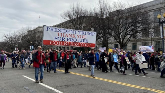 Участники марша держат табличку с надписью "Президент Трамп, спасибо за защиту жизни, да благословит вас Бог"