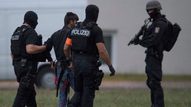 Полицейские в балаклавах сопровождают иракского просителя убежища Али Башара в штабе полиции в Висбадене, западная Германия, 9 июня 2018 года.