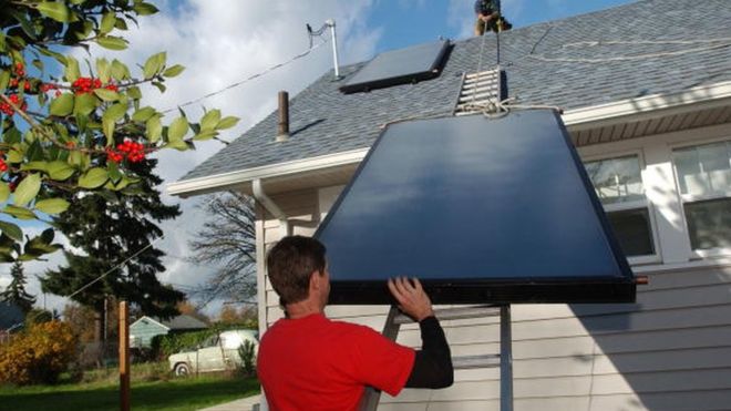 Мужчина устанавливает солнечные батареи для системы горячего водоснабжения в США