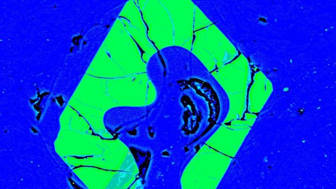 Изображение на электронном микроскопе в ложном цвете кристалла апатита (зеленого цвета) в стекле из смолы (синее)