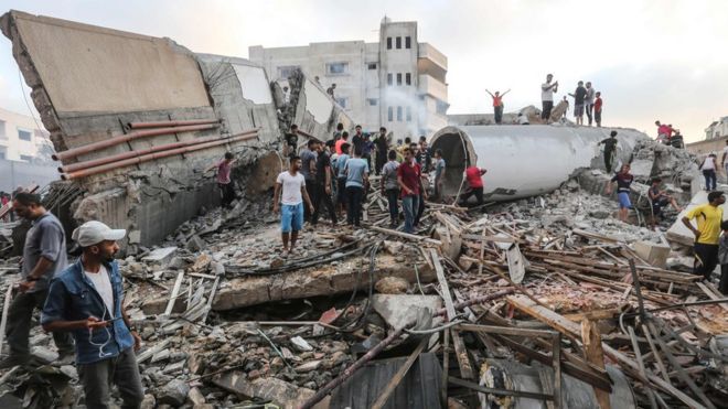 Палестинцы обыскивают останки культурного центра, разрушенного в результате авиаудара Израиля по Газе (9 августа 2018 года)