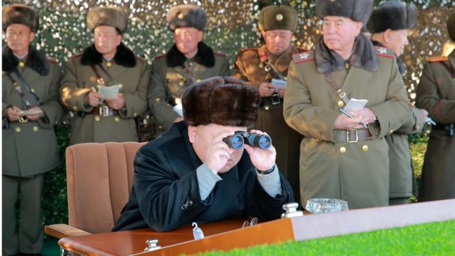 Северокорейский лидер Ким Чен Ын смотрит в бинокль на боевую стрельбу среди батарей многоразового запуска армейских ракетных систем (MLRS) на недатированной фотографии, выпущенной Корейским центральным информационным агентством Кореи (KCNA) в Пхеньяне 21 декабря 2016 года. Премьер-министр Японии Абэ (слева) заявил в понедельник, что ожидает от Трампа более жесткой линии в отношении Северной Кореи
