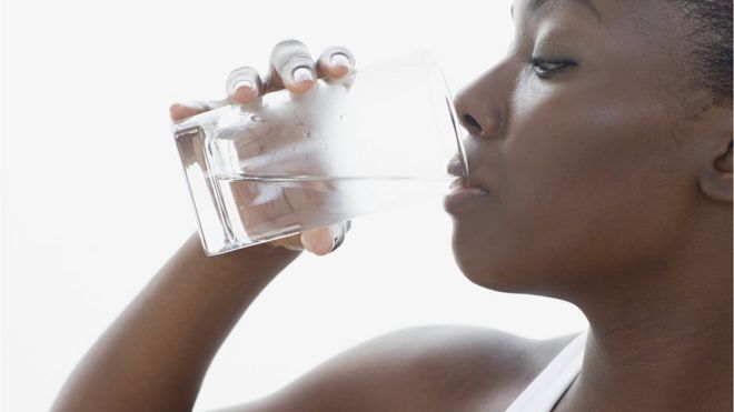 Une femme boit un verre d'eau