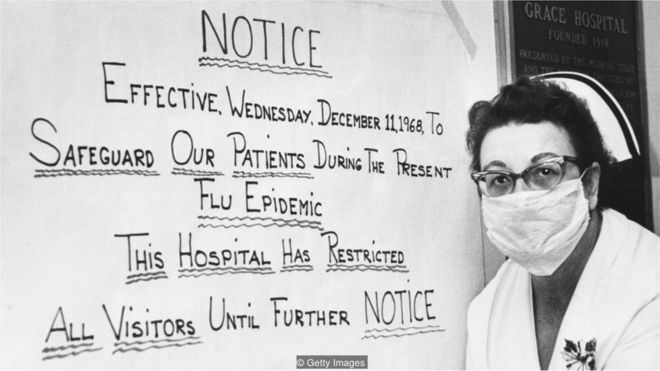 Enfermeira em frente à cartaz da gripe espanhola