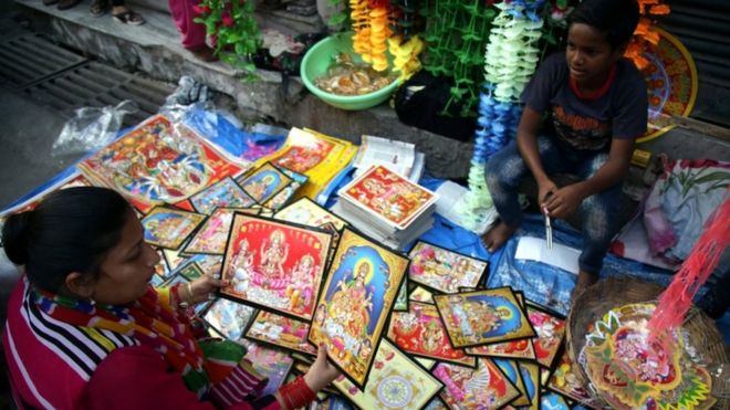 ஜம்முவில், தீபாவளியை முன்னிட்டு தெய்வங்களின் புகைப்படங்களை விற்பனை செய்யும் பெண்.