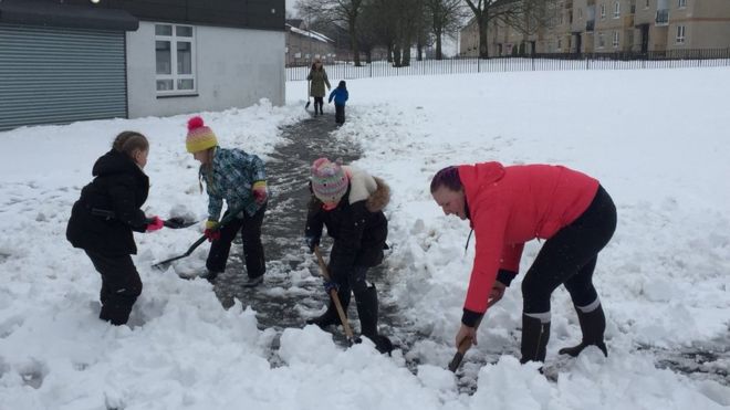 Родители и дети убирают снег на воскресном утреннем первосвященнике в Глазго
