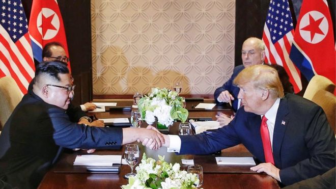 Президент США Дональд Дж. Трамп (справа) и лидер Северной Кореи Ким Чен Ын (слева) пожимают друг другу руки за столом во время расширенной двусторонней встречи