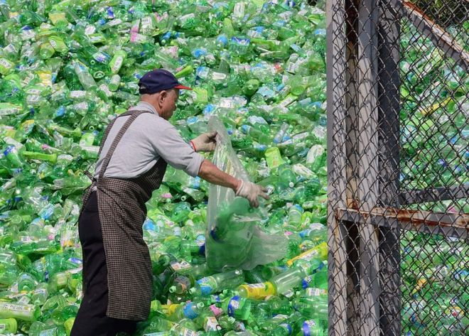 Волонтер перебирает пластиковые бутылки на заводе по переработке в Тайбэе, Тайвань