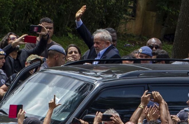 Lula deixando velório do neto, Arthur, escoltado pela polícia, sob o olhar de militantes e apoiadores
