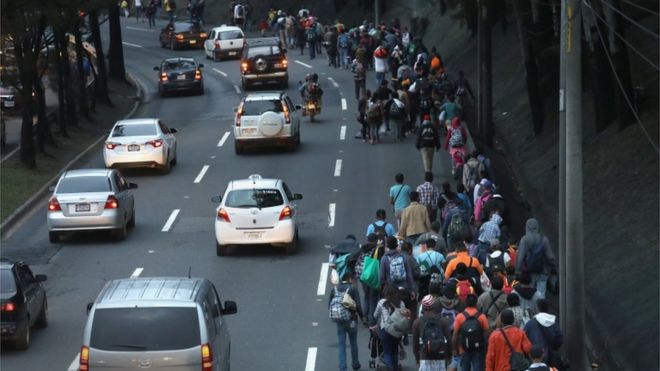 Мигранты гуляют рядом с машинами по дороге