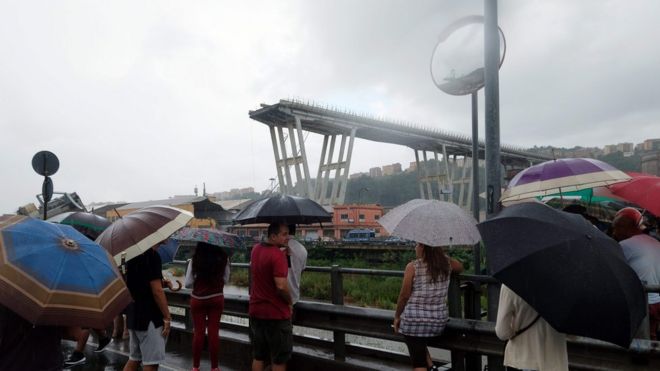 Люди собираются, чтобы наблюдать за спасательной операцией после обрушения участка гигантского автодорожного моста, 14 августа 2018 года в Генуе