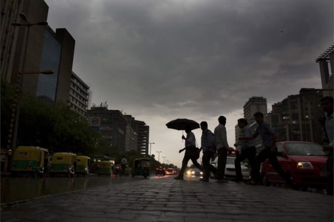 Индийские жители пригородной зоны идут домой под дождем в Нью-Дели, Индия, в понедельник, 23 мая 2016 года.