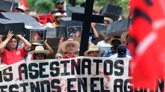 Члены Объединенного крестьянского движения (MUCA) Баджо Агуана несут ложные гробы с фотографиями товарищей, убитых в столкновениях в результате земельного конфликта, во время марша, посвященного 191-й годовщине независимости страны, в Тегусигальпе, 15 сентября 2012 года.
