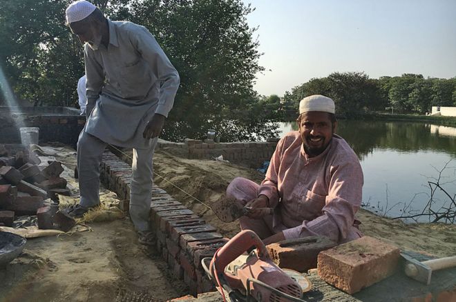 Раджа Хан улыбается, когда он работает над мечетью
