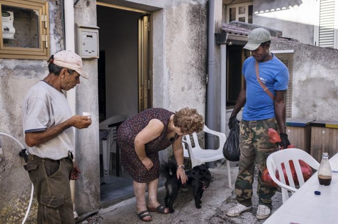 Бьяджо и Даниэль беседуют с местной женщиной во время их от двери до двери мусора и утилизации отходов.