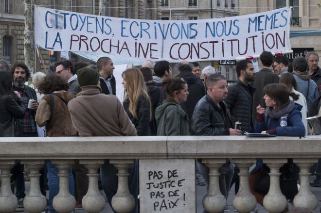 Люди собираются рядом со знаменем, на котором написано «граждане, давайте напишем себе следующую конституцию». на площади Республики в Париже