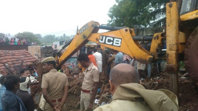மேட்டுப்பாளையம் அருகே மழையால் இடிந்த வீடுகளின் இடிபாடுகளை அகற்றும் மண்வாரி இயந்திரம்.