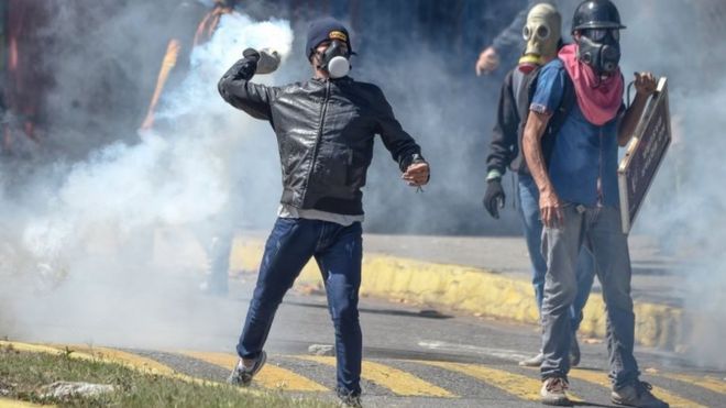 Протестующий выбрасывает газовый баллончик во время столкновений с полицией в знак протеста против гибели боевика Оскара Переса в Каракасе 22 января 2018 года.
