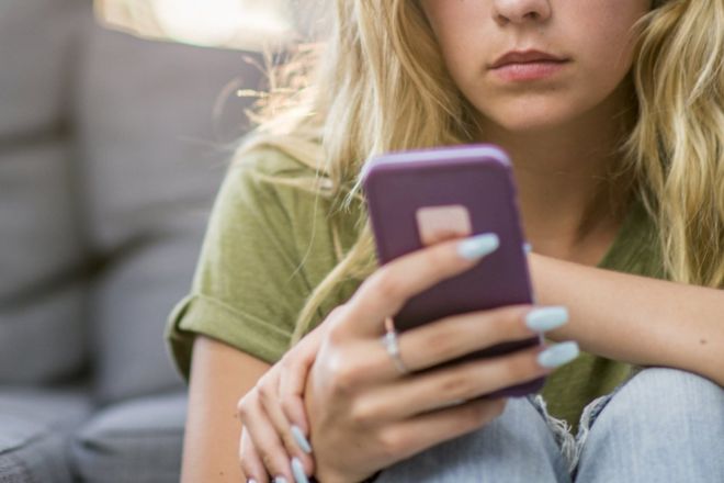 A girl looking solemnly at her smartphone.