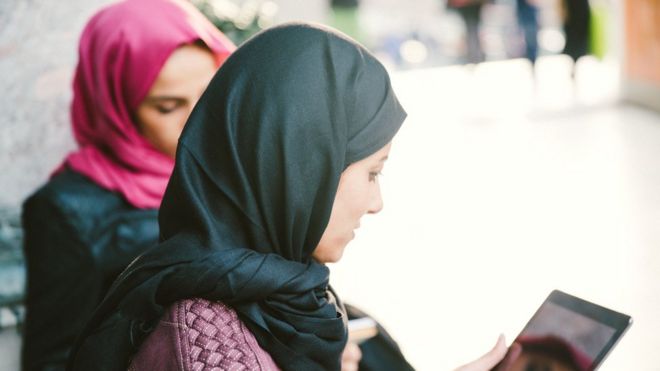 Могло повлиять не только на мусульманских женщин, носящих платки, но и на других работающих людей, которые выражают свою религиозную приверженность через одежду и знаки отличия. Женщины в хиджабе смотрят на планшет (изображение)