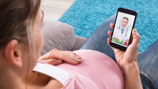 Беременная женщина консультируется с врачом на своем смартфоне