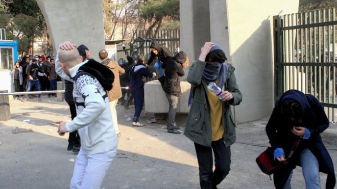 Iranian students run for cover from tear gas at the University of Tehran during a demonstration