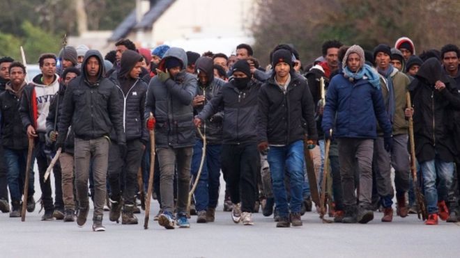 Группа мигрантов несет палки во время столкновений в Кале 1 февраля 2018 года.