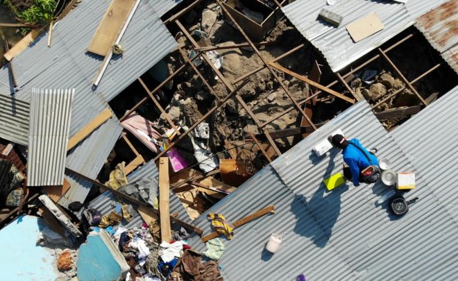 People on the roof of a collapsed building in Palu