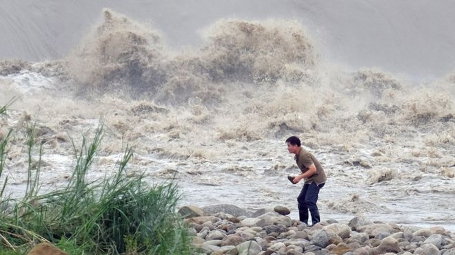 Местный житель собирает камни у реки Синдиан после того, как тайфун Дуцзюань прошел в Новом Тайбэе (29 сентября 2015 г.)