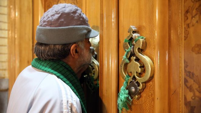 A man kisses the closed door of the Fatima Masumeh shrine in Qom
