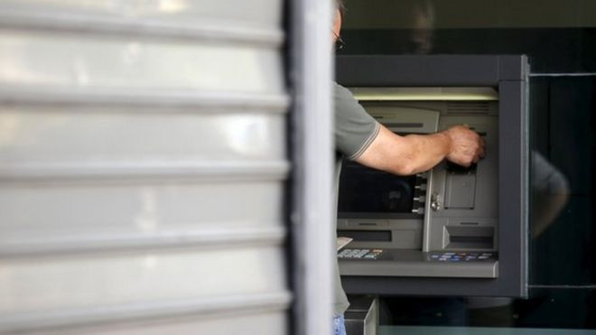 Мужчина снимает деньги в банкомате отделения Альфа-банка в центре Афин