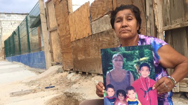 Irma Vargas Laguna en la puerta de su casa en Ciudad Juárez con una foto de su hija y sus nietos