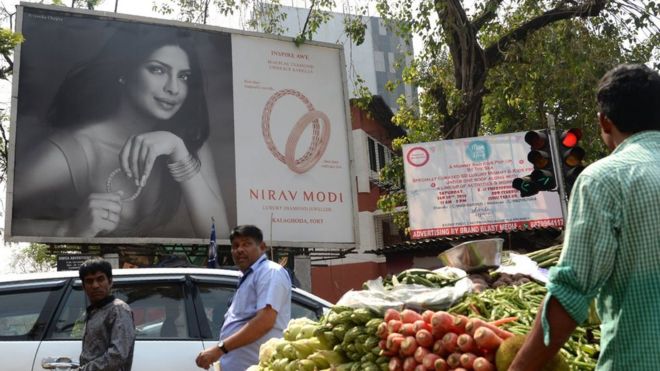 Индийцы проходят мимо рекламного щита с изображением болливудской актрисы Приянки Чопры, рекламирующей магазин роскошных ювелирных украшений Nirav Modi в Мумбаи 15 февраля 2018 года