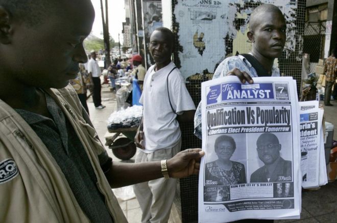 Уличный газетный киоскарь в Либерии представляет первые полосы газеты, 7 ноября 2005 года, в Монровии, накануне второго тура президентских выборов в Либерии. Его популярность оставалась высокой в ??течение прошедших 12 лет
