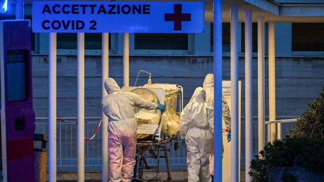 Profissionais de saúde carregam paciente em maca por corredor externo de hospital recém-construído em Roma