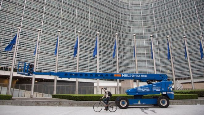 Мужчина проезжает на своем велосипеде мимо флагов ЕС перед штаб-квартирой ЕС в Брюсселе в пятницу, 24 июня 2016 г.