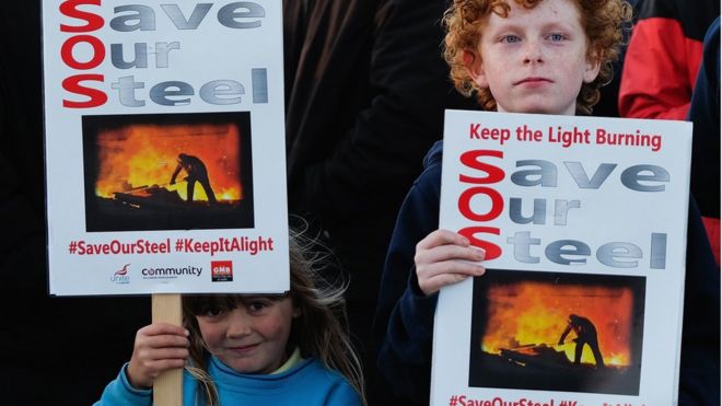 24 сентября 2015 года в Редкаре, Англия, девочка и мальчик держат плакаты, которые демонстрируют рабочие из стали и их семьи. Мир сталкивается с огромным избытком стали - в настоящее время фактически используется только две трети производимой стали