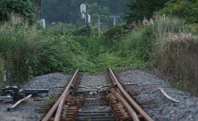 Ржавый железнодорожный путь линии Джобан покрыт сорняками возле станции Тацута в городе Нараха - первом из семи эвакуированных городов, которые были открыты после катастрофы 2011 года