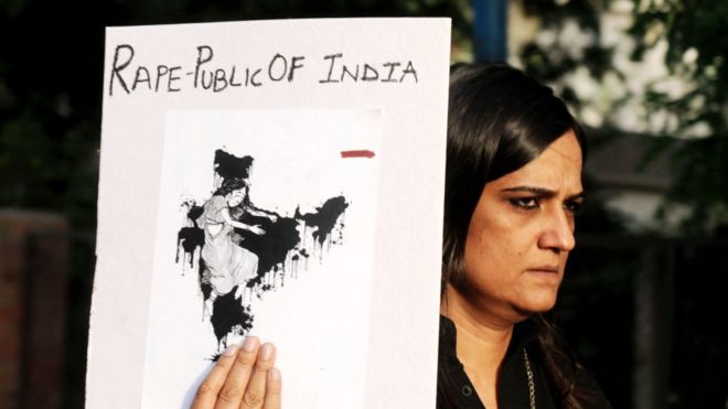 Imagem mostra mulher em protesto em abril de 2018 contra o caso brutal de estupro e assassinato de menina de 8 anos em Kathua, na Índia. Ela segura cartaz que faz trocadilho com o nome República da Índia, para chamar o país de República do estupro