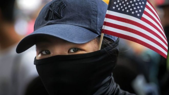 带着美国国旗游行的蒙面示威者