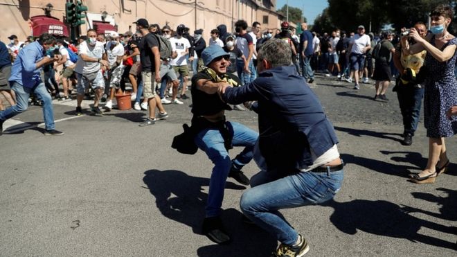 A plain-clothed police officer confronts a demonstrator as members of far-right political movements and hardcore football fans protest together against the economic crisis caused by the coronavirus outbreak and its handling by the Italian government, in Rome, Italy, on 6 June 2020