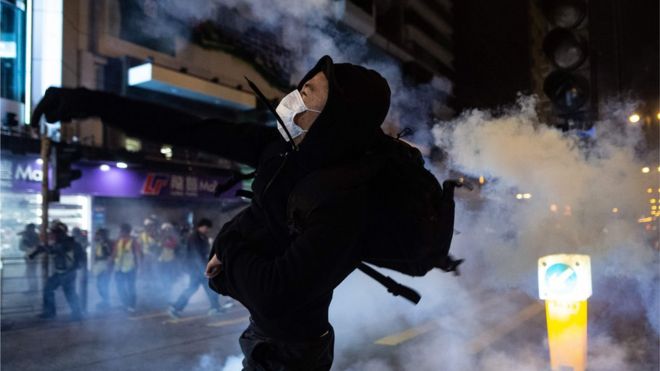 抗議者は、警察が催涙ガスを発射した後、香港のヨルダン地区での抗議行動で傍観者を解散させた後、2019年12月25日に反応する