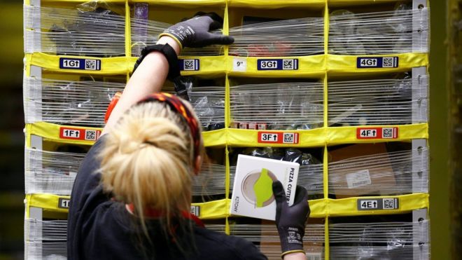 Сотрудник работает над складыванием предметов в роботизированных стеллажных системах в центре выполнения заказов Amazon в Кенте, штат Вашингтон, США, 24 октября 2018 года.