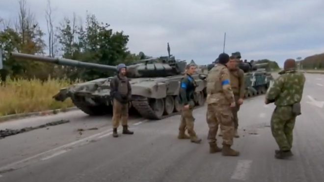 Ukrainian soldiers stand by a Russian tank