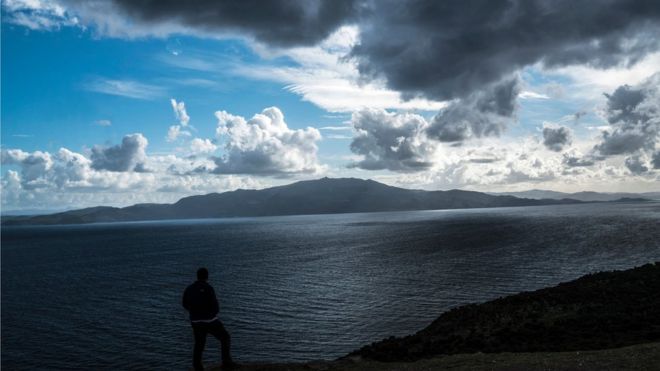 Мужчина смотрит на греческий остров Лесбос с побережья Турции, в пасмурный и ветреный день 4 марта 2016 года