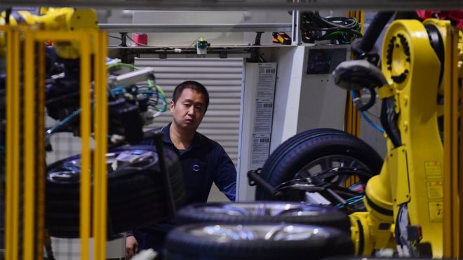 На этом снимке, сделанном 22 ноября 2017 года, показан сотрудник, который смотрит на колеса на производственной линии автомобилей на заводе BMW в Шэньяне в северо-восточной провинции Китая Ляонин.
