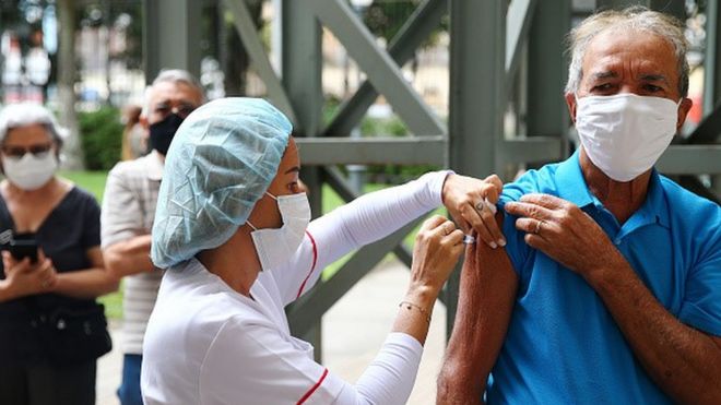 Enfermeira aplicada vacina no braço de homem