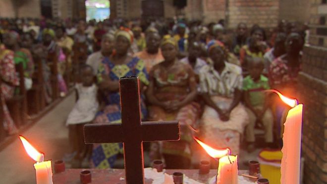 Люди сидят в церкви с крестом и свечами на переднем плане