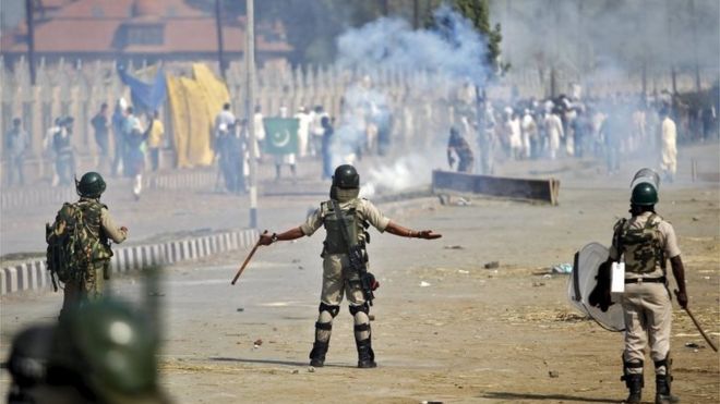 Индийский полицейский указывает на демонстрантов из Кашмира во время акции протеста после молитвы Ид аль-Адха в Сринагаре, 25 сентября 2015 года.