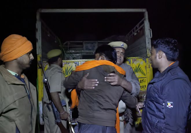 Полицейский обнимает Навала Кишора Шарму после того, как его группа преследует грузовик в ноябре 2015 года